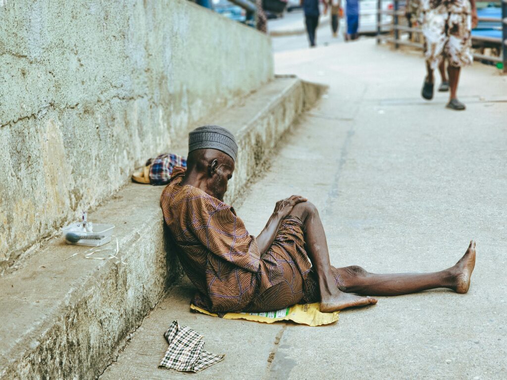 pexels-photo-30626689-30626689 A senior man in traditional clothing rests outdoors on a city street.